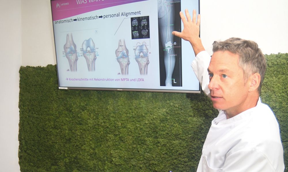Dr. med. Andreas Bell zeigt auf eine Präsentation an einem Bildschirm.