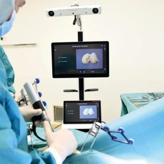 Robotergestütztes Navigationssystem während einer Knieoperation mit Monitoranzeige und chirurgischem Instrument.