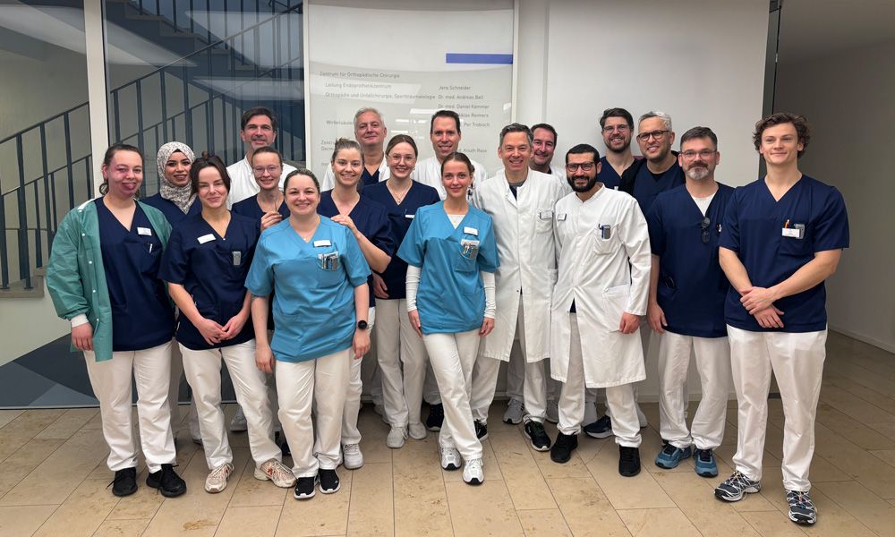 Gruppenfoto eines Klinikteams in Arbeitskleidung.